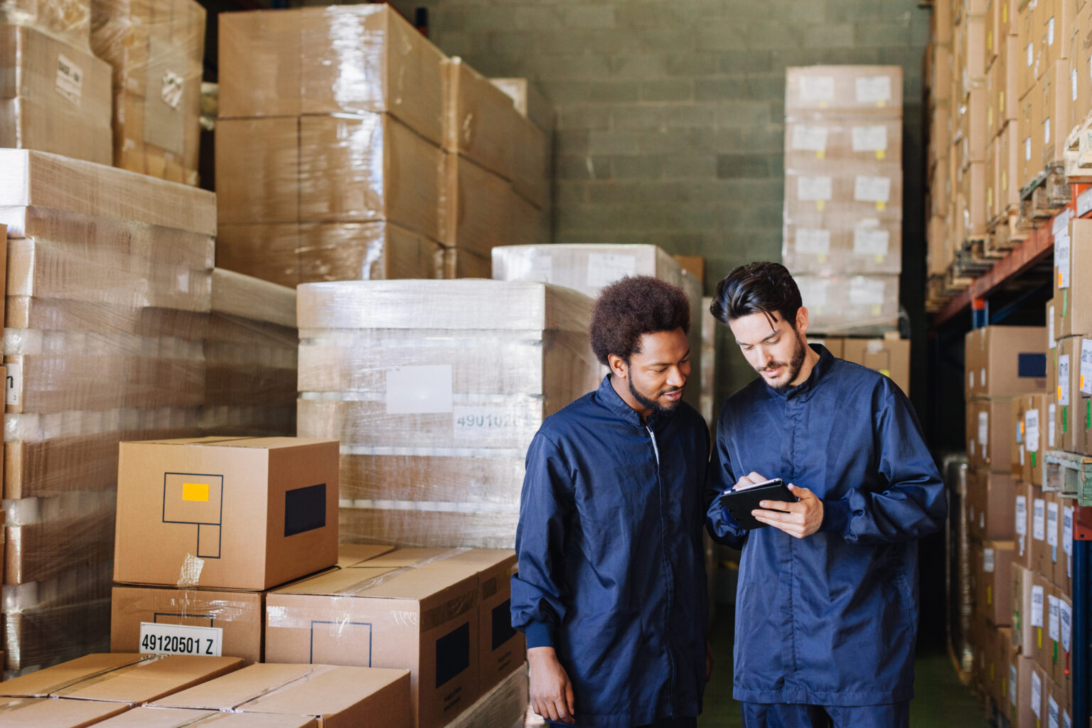 Two workers using a digital tablet in a warehouse.